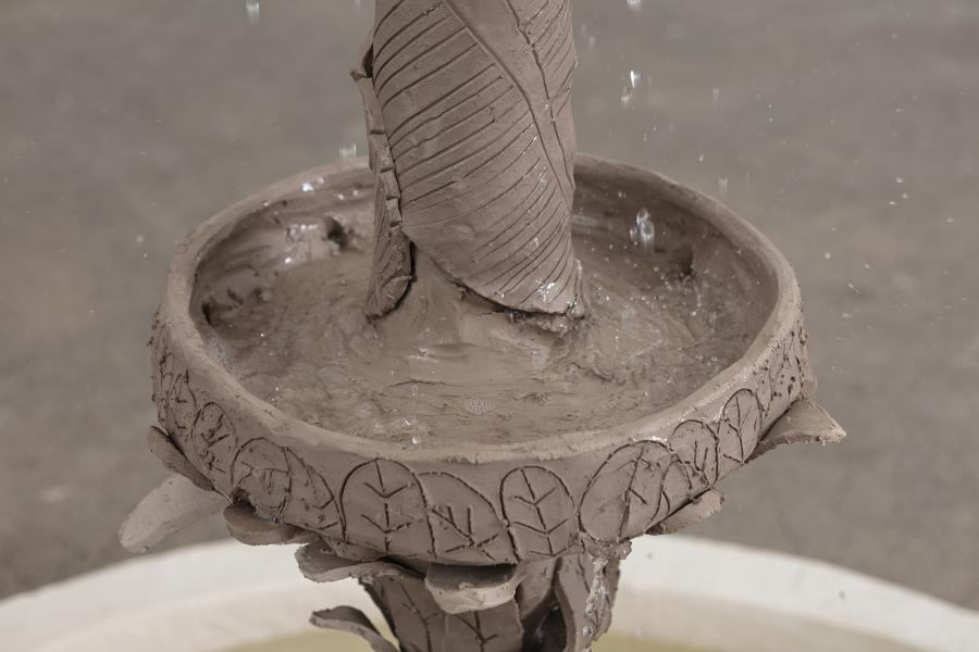detail image of the center of a fountain floor sculpture made of clay with water at the base