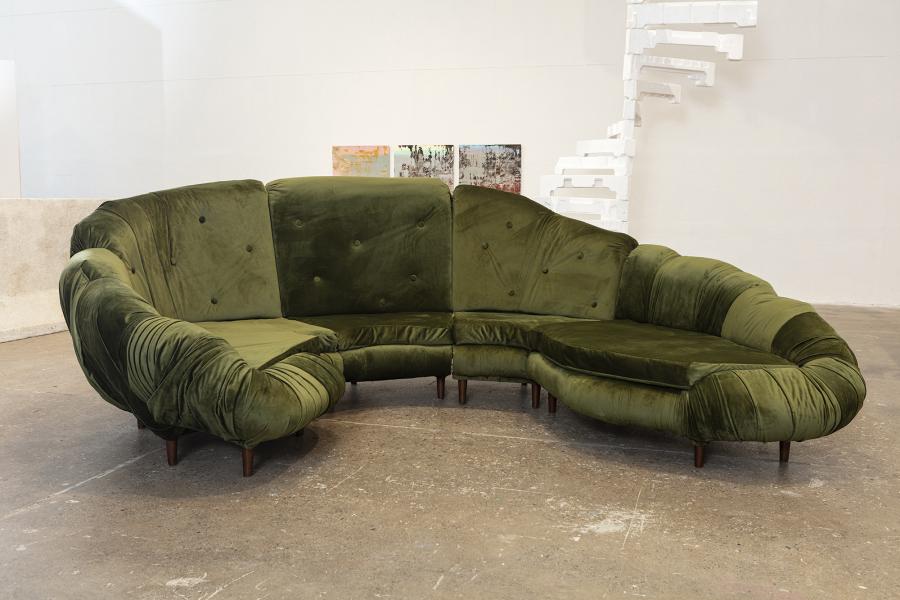 Round green couch resembling topiary. Upholstery is dark green velvet