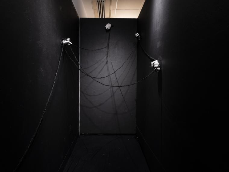 installation of a dark space with plaster hands mounted to the walls