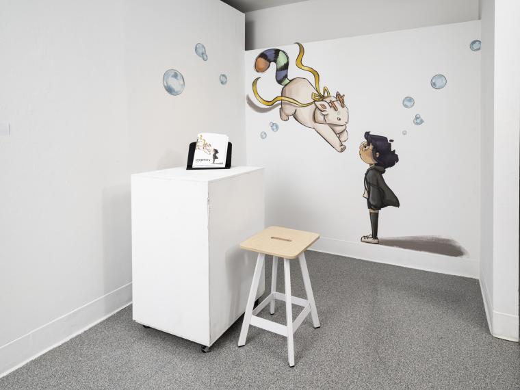 installation image of illustrations on walls and a book on a pedestal