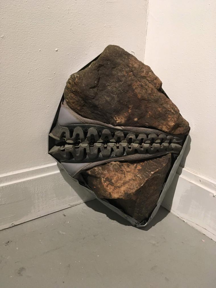 small sculpture placed on the floor combining rocks and shoe soles