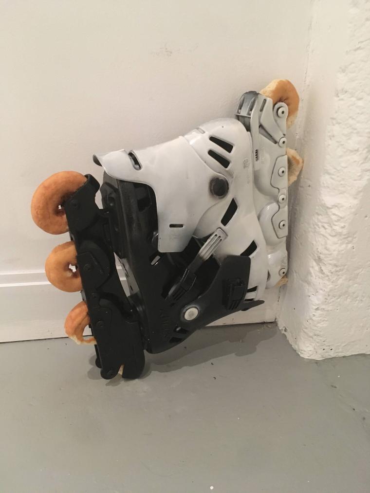 sculpture leaning against the wall using interlocking black and white Rollerblades and donuts for wheels